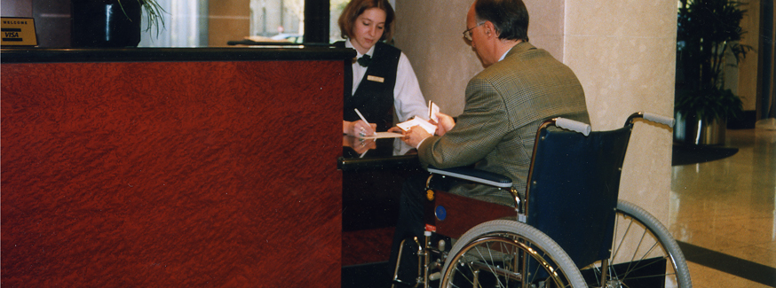 Person mit Rollstuhl am Hotelempfang